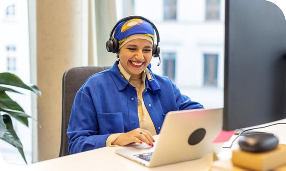 A businessperson works at a desk using a laptop and monitor. 
