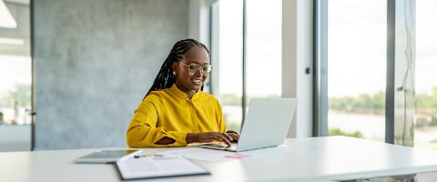 Professional woman working at her laptop in a bright sunlit office