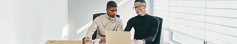 Two professional men looking at a laptop in a conference room